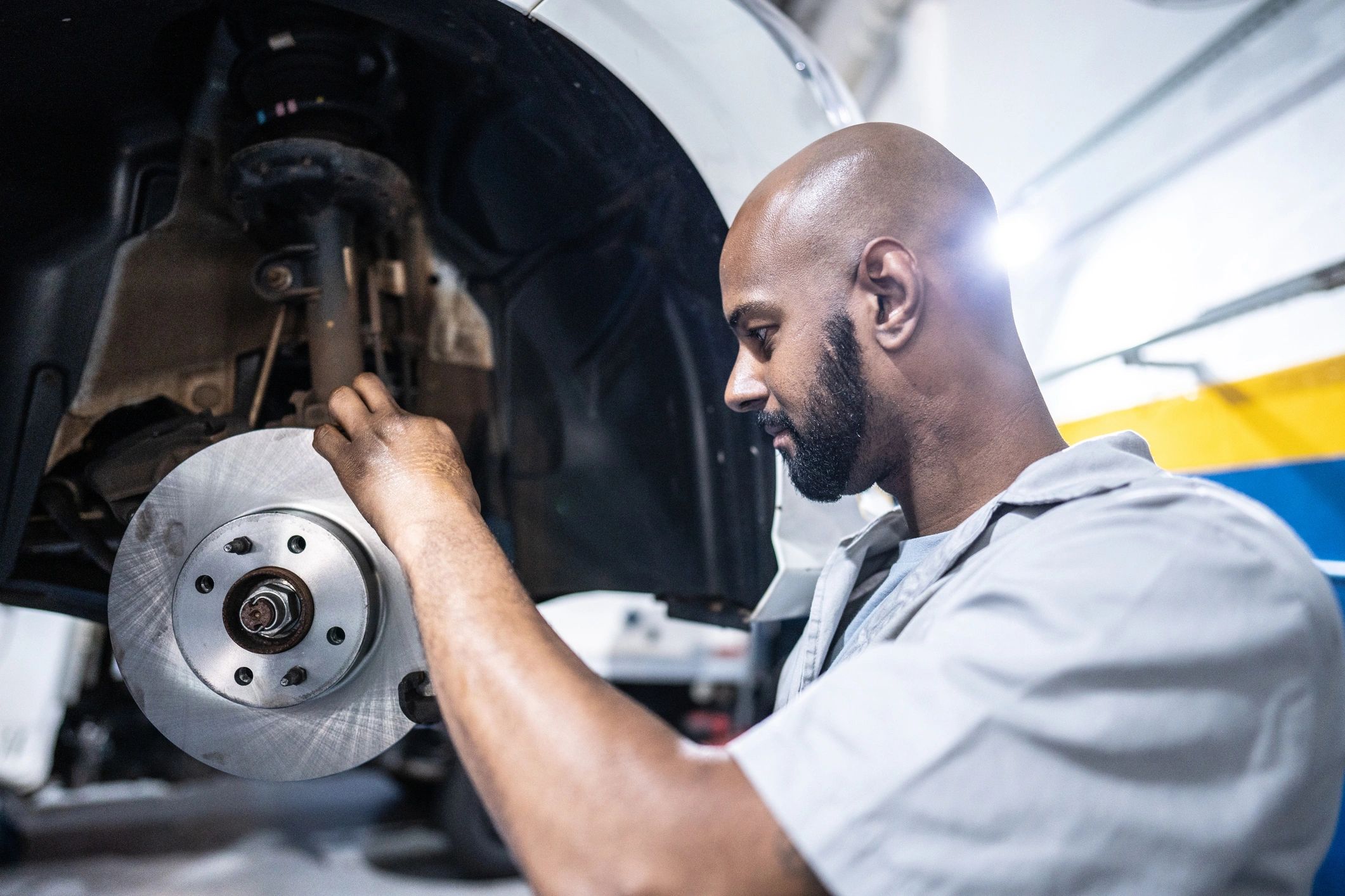 Mechanic inspecting a vehicle brake assembly in the shop