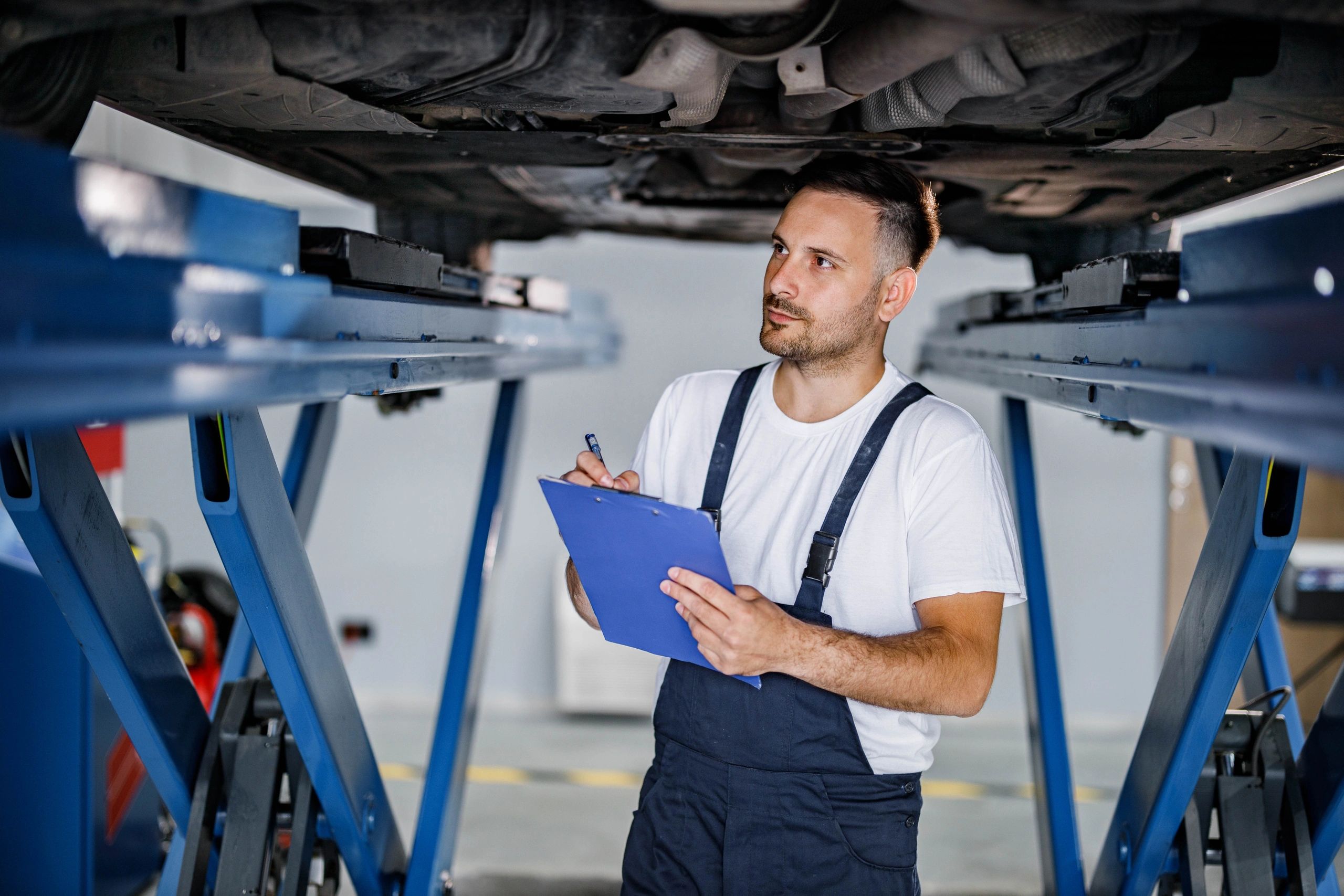 Mechanic writing notes under a vehicle