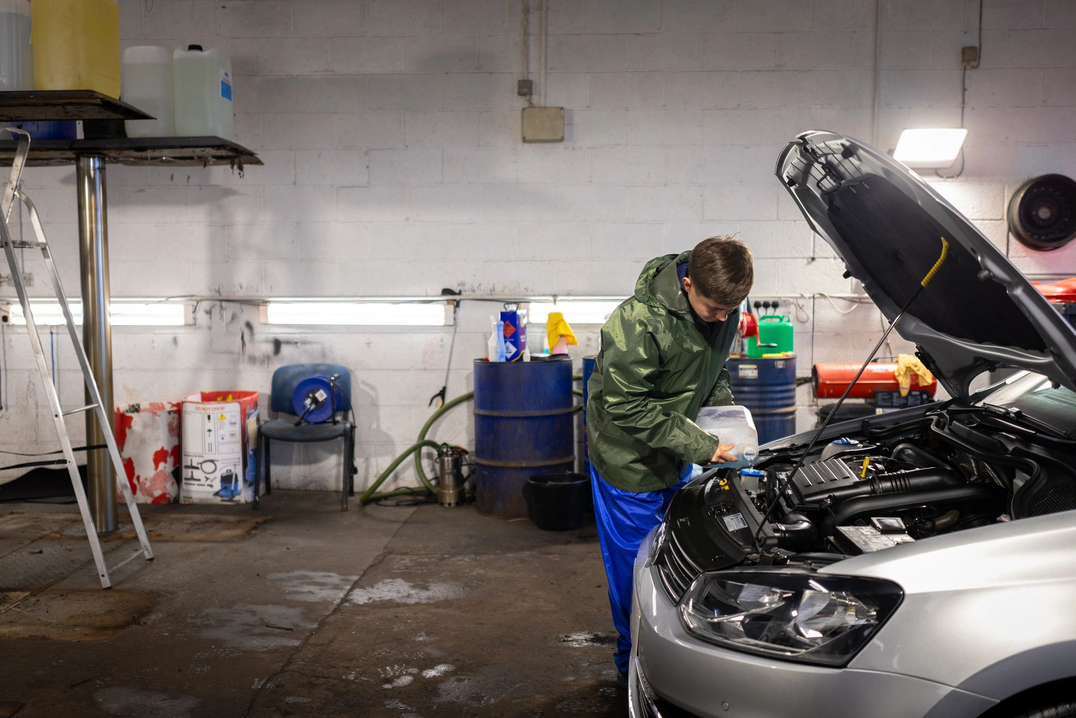 Mechanic topping off windshield washer fluid during routine maintenance service