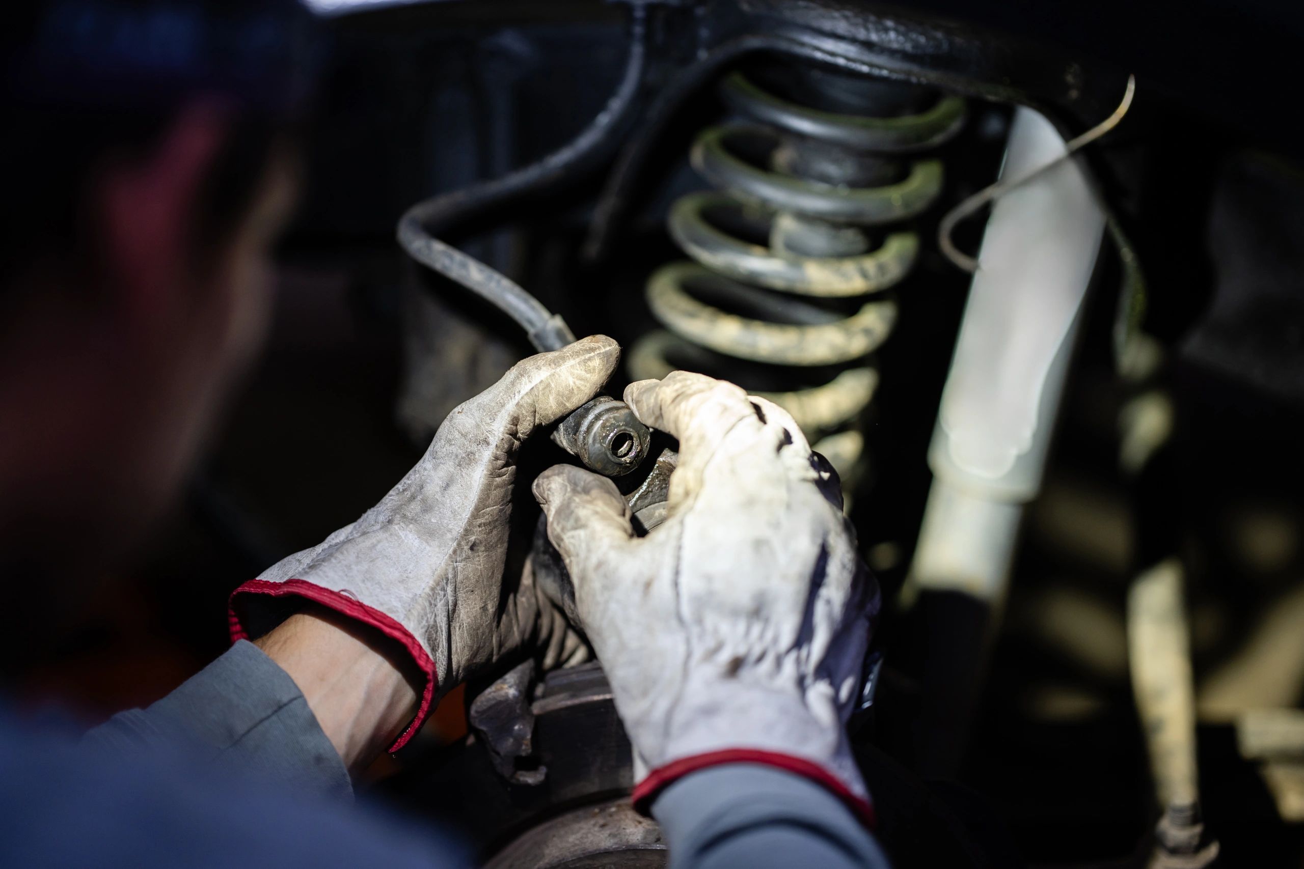 Mechanic hands working on vehicle suspension and brake components